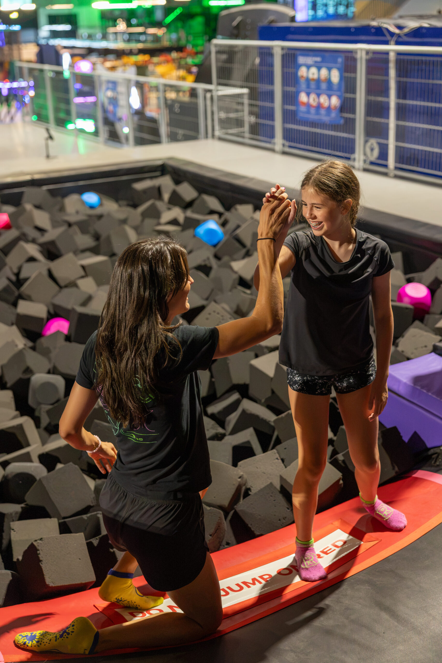 Enfant célébrant ses progrès avec sa coach au trampoline pendant le Jump Camp à La Ruche à Fribourg